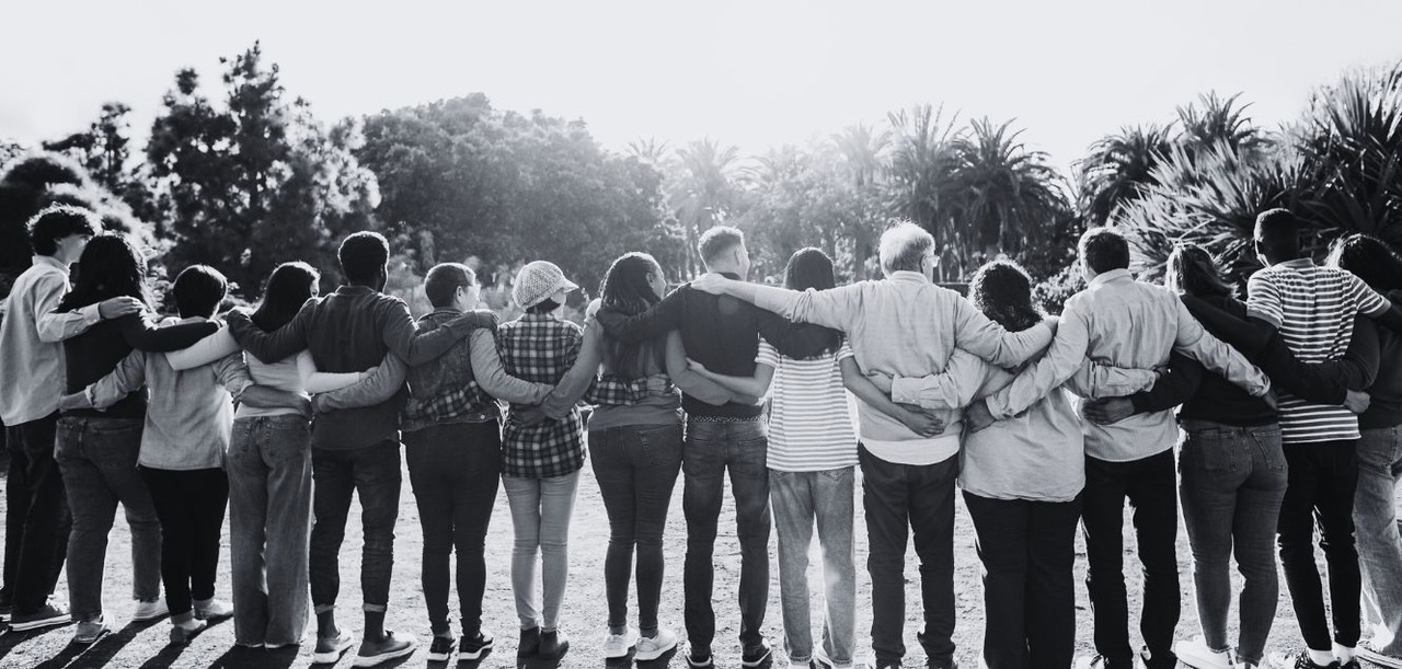 Group of people with their arms around each other.